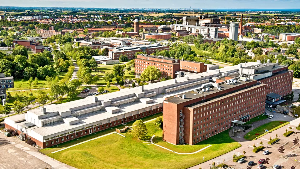 A photo from above over a big red building surrounded by trees and lawns. Photo