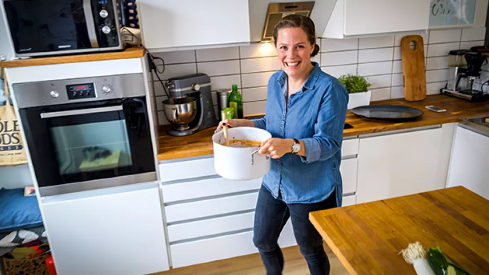 Woman in a kitchen carrying a casserole