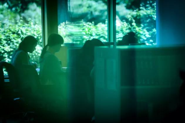 Students sitting and reading at campus, seen through a green glas. Photo Kennet Ruona.