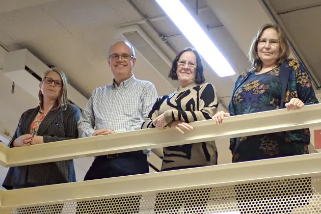 Four people leaning against a rail. Photo