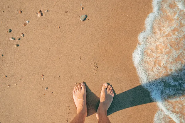 Feet on sandy beach. Mostphotos.