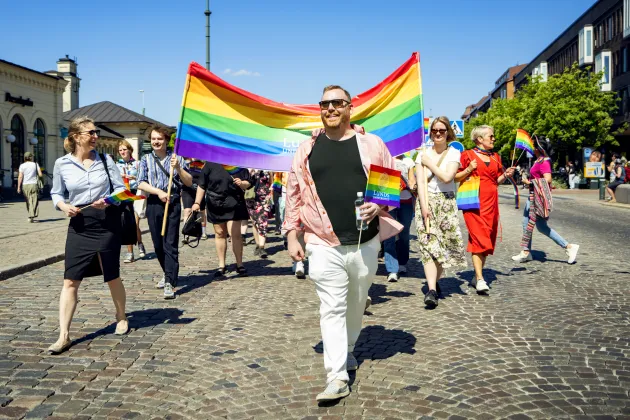 People walking in the Pride parade with rainbow flags.