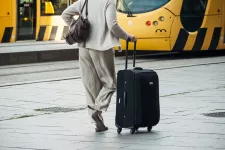 Woman walking with suitcase in front of train-station.