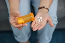 En hand häller upp tabletter ur en pillerburk.