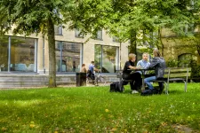 Two persons sitting in the grass on campus.