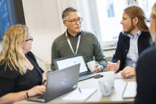 Four persons discussing in a meeting room.