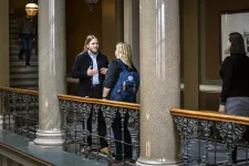 Two persons standing and talking seen from a distance.