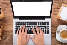 Two hands on a laptop with a coffee beside.