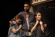 A scene from a theatre play with a man holding two women.