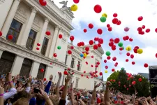 Crowd with people and balloons in front of the University Main Building.