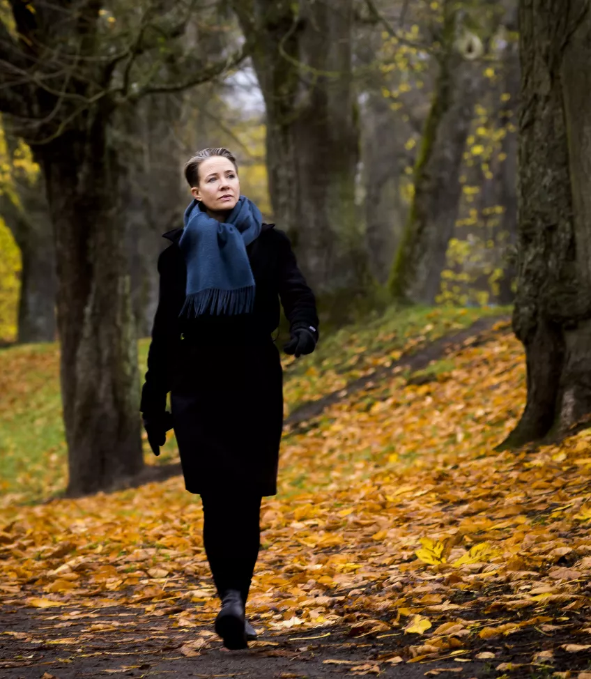 A woman walks on yellow leafs in a forest. Photo.