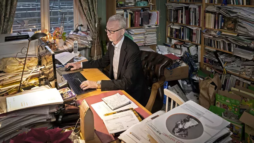 a man at an overloaded desk. Photo