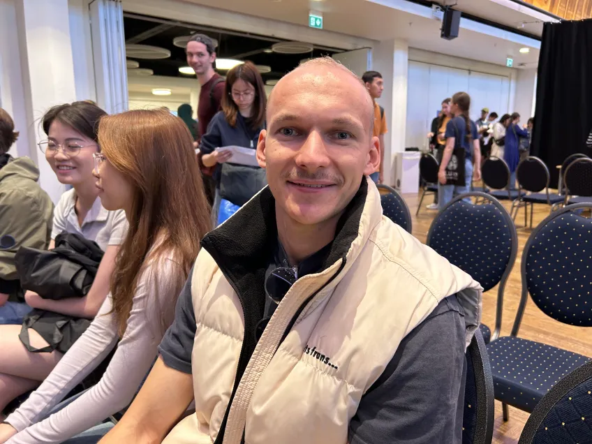 A man sitting looking in the camera smiling.